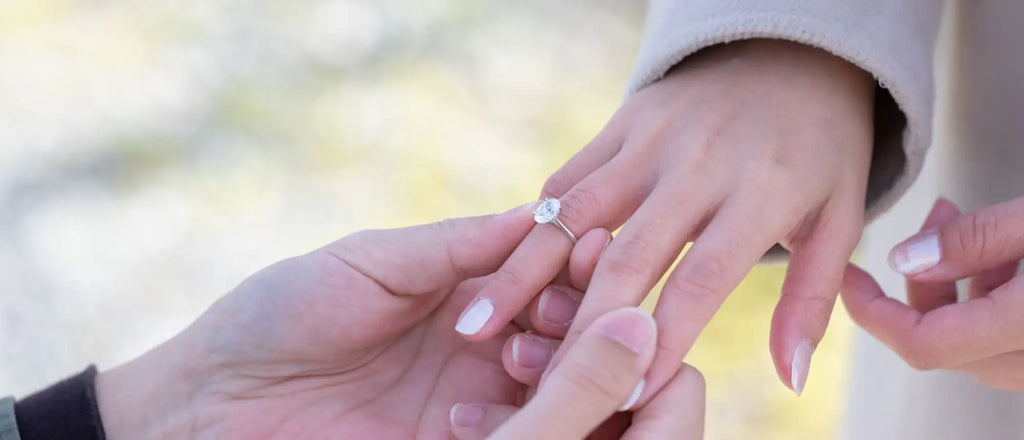 A delicate silver band ring featuring a single, sparkling round-cut diamond at its center.