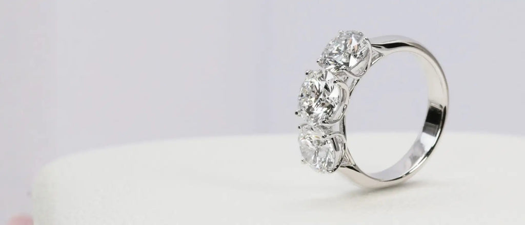 A sleek platinum three-stone diamond ring with brilliant-cut stones set in a classic, elegant design.